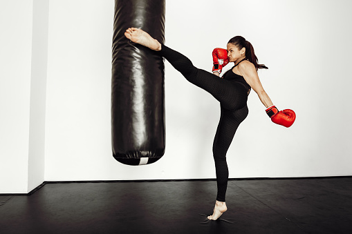 Woman athlete in red boxing gloves hits a pear in a sports gym