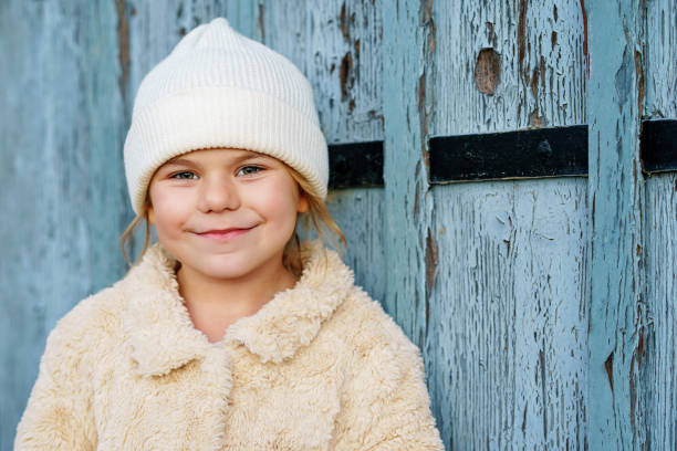 추운 겨울날 야외에서 사랑스러운 어린 소녀의 초상화. 따뜻한 옷을 입고 니트 모자와 코트를 입은 귀여운 미취학 아동. 스톡 사진