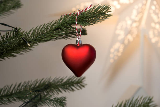 christmas banner with heart shaped red ornamnets hanging on tree with lights bokeh. Copy space banner