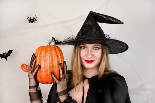 istock Autumn holidays banner with cute witch holding pumpkin on white background,. October 31 concept.Halloween party 1650802472