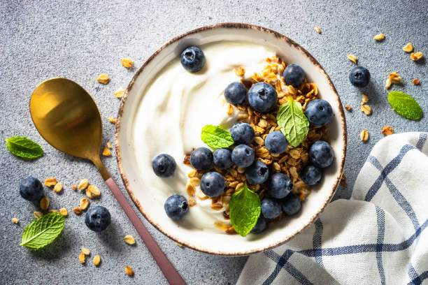 istock Greek Yogurt with granola and fresh blueberry at light stone table. 1650827831