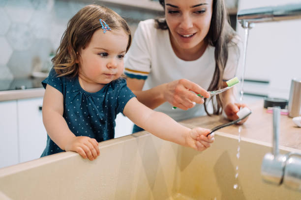 istock Mother and daughter brushing teeth together. 1650829983