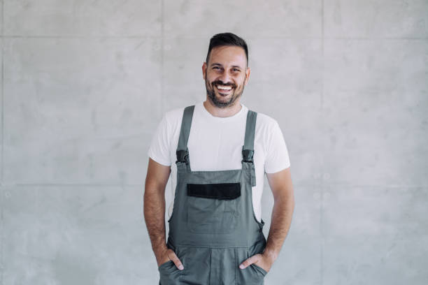 istock Young male worker in an overall uniform posing at his workplace. 1650830091