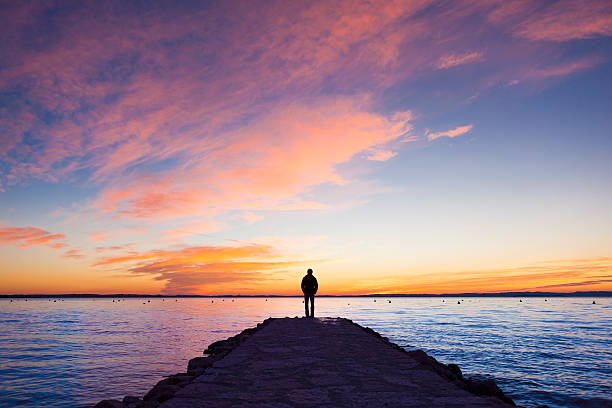 hombre de pie en el embarcadero - sunset sea tranquil scene sunrise fotografías e imágenes de stock