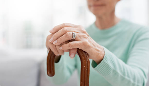 istock Hands, walking stick and elderly woman with walking stick on a sofa for balance, support and mobility. Walk, aid and old female at senior care facility with disability, dementia or chronic arthritis 1650853719