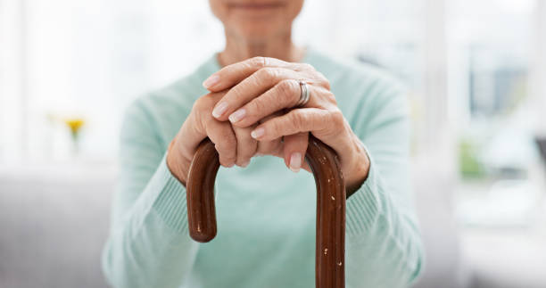 istock Hands, walking stick and elderly woman with walking stick on a sofa for balance, support and mobility. Walk, aid and old female at senior care facility with disability, dementia or chronic arthritis 1650853770