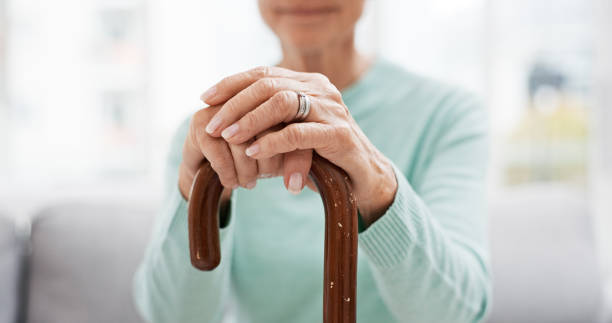 istock Hands, walking stick and elderly woman with walking stick on a sofa for balance, support and mobility. Walk, aid and old female at senior care facility with disability, dementia or chronic arthritis 1650853772