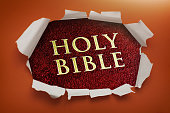 Holy Bible cover and title revealed through hole in paper with torn jagged edges, with deep orange in background
