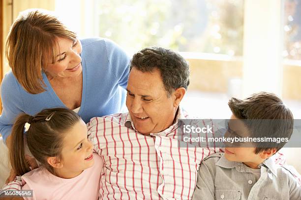 Hispanic Grandparents With Grandchildren Relaxing On Sofa At Hom Stock Photo - Download Image Now