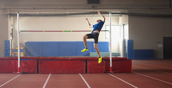 Male athlete training high jump over a four metre long horizontal bar. Sport and endurance concept.
