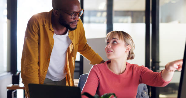 istock Corporate black man, woman and point at computer, schedule or planning for learning at marketing job. Mentor, teaching and help for man, employee and reading on pc, internet or social media for SEO 1650858286