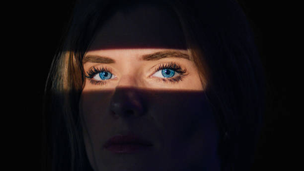 istock Woman in black.The light falls only on her eyes. 1650858975