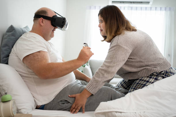 współczesna miłość: różnorodna para odkrywa wirtualną rzeczywistość w łóżku w domu - cyberseks zdjęcia i obrazy z banku zdjęć