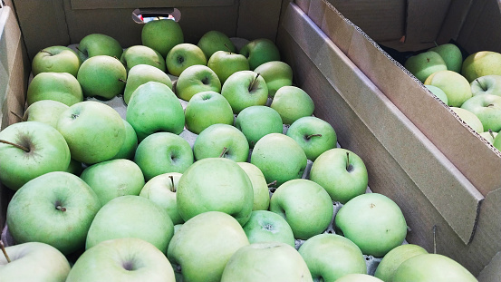 Green apples in boxes. Fresh fruits in local farmers market or supermarket. Discount. Grocery shopping. Greengrocer. Natural food. Store. Rich harvest. Supply products. Retail industry. Purchase