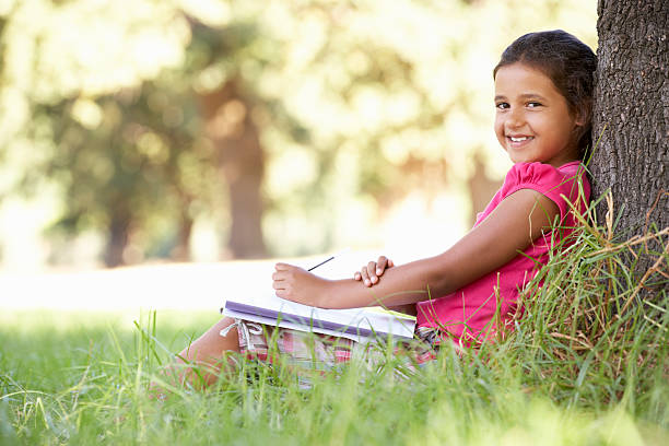 istock Young Girl Sketching In Countryside Leaning Against Tree 165086869