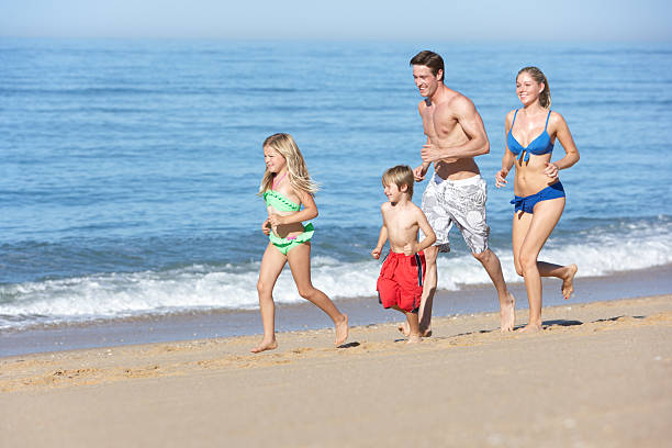istock Family Enjoying Holiday Running Along Beach 165087108