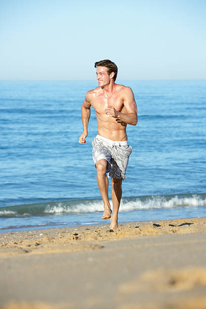 istock Young Man Running Along Summer Beach 165087185