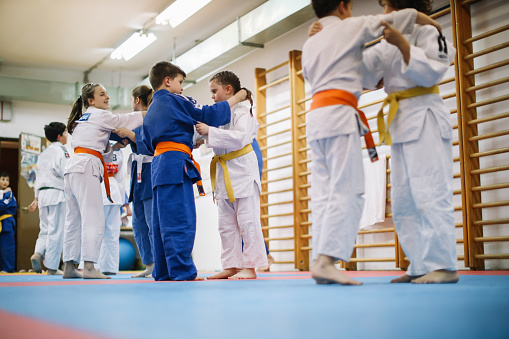 9 - 14 year old kids training judo with their sensei teacher at the dojo gym training ground.