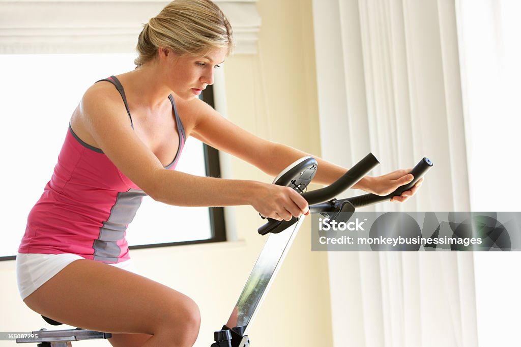 Mujer joven en bicicleta fija - Foto de stock de Bicicleta estática libre de derechos