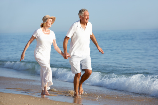 Senior Couple Enjoying Beach Holiday Running Along Shoreline