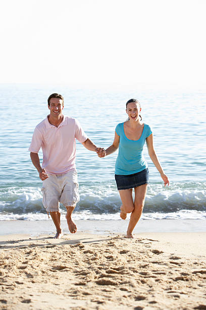 istock Young Couple Running Along Beach On Holiday 165087514