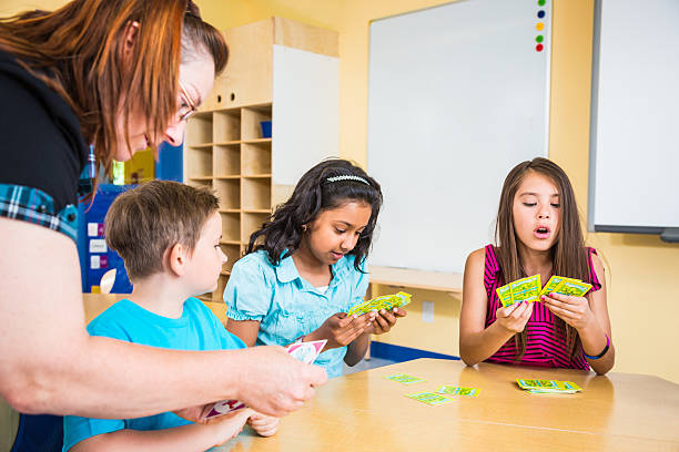 Teacher and school children playing card game Teacher and school children playing card game in classroom. Taken on Toronto'lypse 2012. Playing cards are Property relased by http://www.istockphoto.com/diane555. long hair sitting child schoolboy stock pictures, royalty-free photos & images