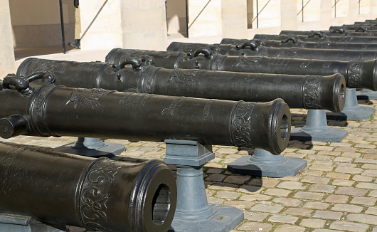 The historic Army Museum from 1905 in Paris, France. Pictures are made outside of the museum building, in the main courtyard, showing inner facade and the collection of bronze cannons. You do not have to pay for visiting this yard. Pictures made on 02/19/2023.