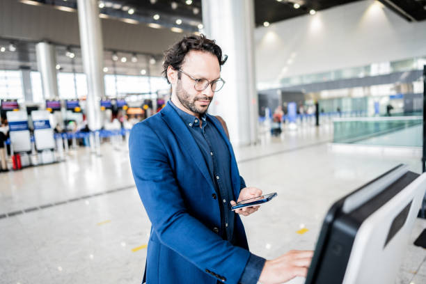 istock Businessman using phone while checking in at airport self-service machine at airport 1650912261
