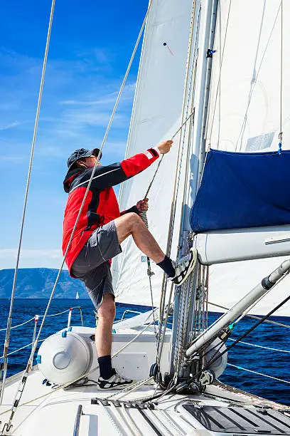 Sailor is controlling hoisting the mainsail.