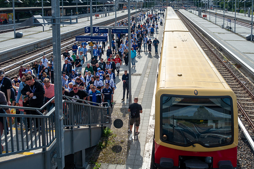 Germany, Berlin, August, 04, 2023 -High angle view of arriving S-Bahn with many passengers on platform at Station Berlin Olympiastadion