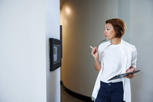 istock Condo building security inspection: female claim agent with digital tab assessing automated security system panel in condo hall 1650944488