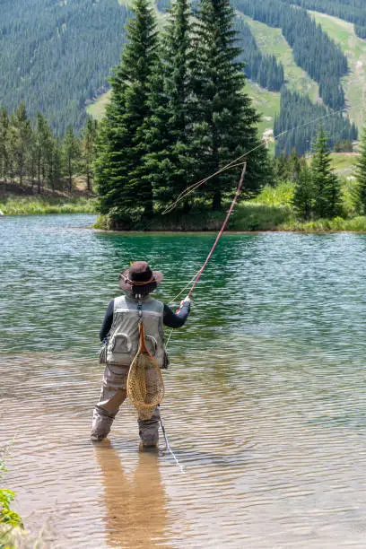 An adult woman, dressed in full fly-fishing attire, fishes Ten Mile Creek,  west of Frisco, Colorado, in the Rocky Mountains, during the month of August.