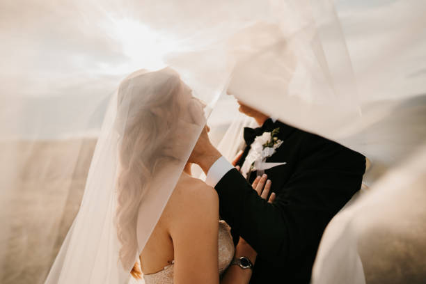 istock Bride and groom under a long veil in nature 1650975794