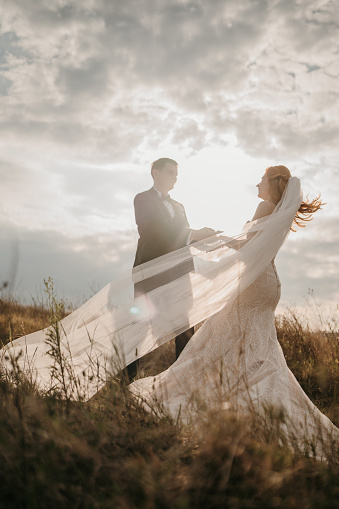 Full length shot of just married young couple dancing in nature with beautiful sky in background