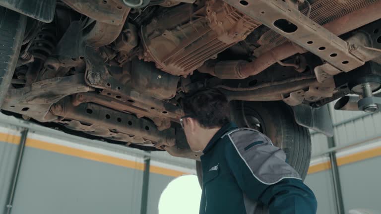 Male mechanic checks the condition of the car's suspension.