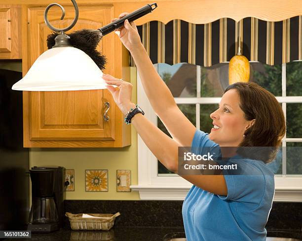 A Woman Using A Feather Duster To Clean A Light Shade Stock Photo - Download Image Now