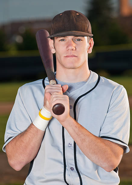 Baseball player poses for portrait with bat over shoulder