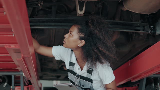 Female mechanic checks the condition of the car's suspension.