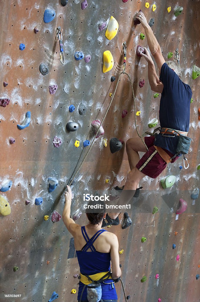 Donna per uomo anziano facendo le soste al coperto Arrampicata su roccia - Foto stock royalty-free di Ambientazione interna