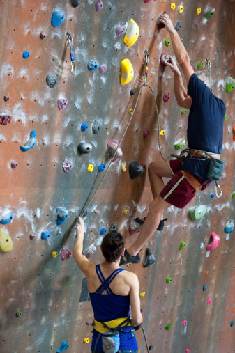 Woman Belays for Senior Man Doing Indoor Rock Climbing