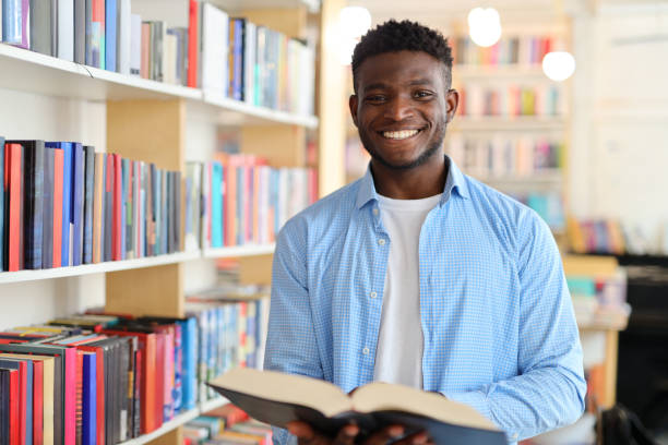 istock A young student happily reads a book in a library, surrounded by bookshelves and knowledge. 1651037787