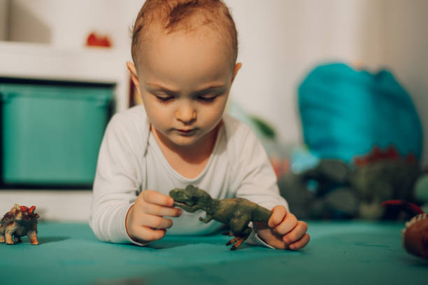 istock A focused little boy is playing and examining his dinosaur toy while staying at home. 1651042882