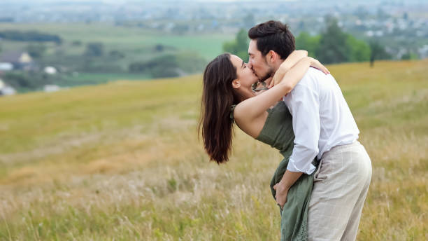 Happy man holds woman in arms on hilly plain