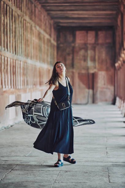 east asian woman in black dress dancing with translucent scarf among columns of ancient temple - taj mahal mahal door temple imagens e fotografias de stock