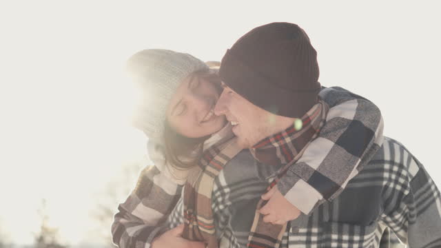 Tenderness and affection on their faces testify to how they bloom together even on cold winter day. Winter romance couple in love against background sun. Often spending time and leisure time together