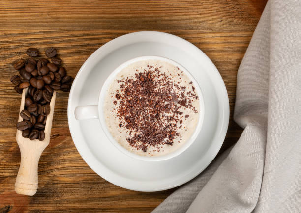 istock Hot coffee cup and coffee beans on brown background top view 1651167472