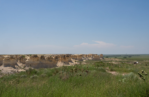 Little Jerusalem Badlands State Park in Kansas with its scenic overlook to the right and yucca plants and prairie grass in the foreground.