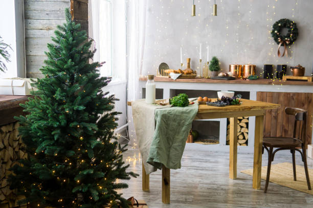Home New Year's interior. Christmas tree with gifts, decorated with garlands in the kitchen. Cozy atmosphere of a home holiday, loft design of the room, Scandinavian style. stock photo