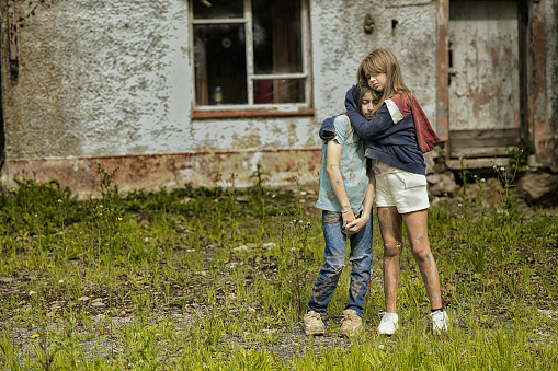 Two young girls standing in their front garden. Posed by models.