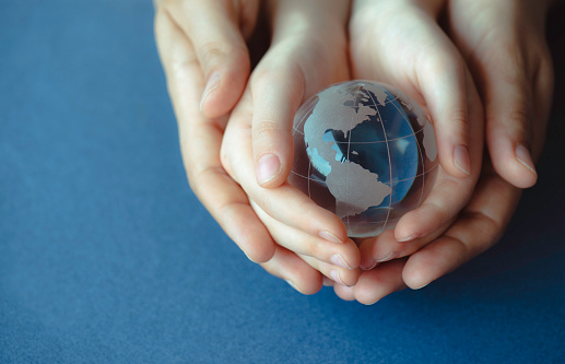 Hands holding a glass globe.